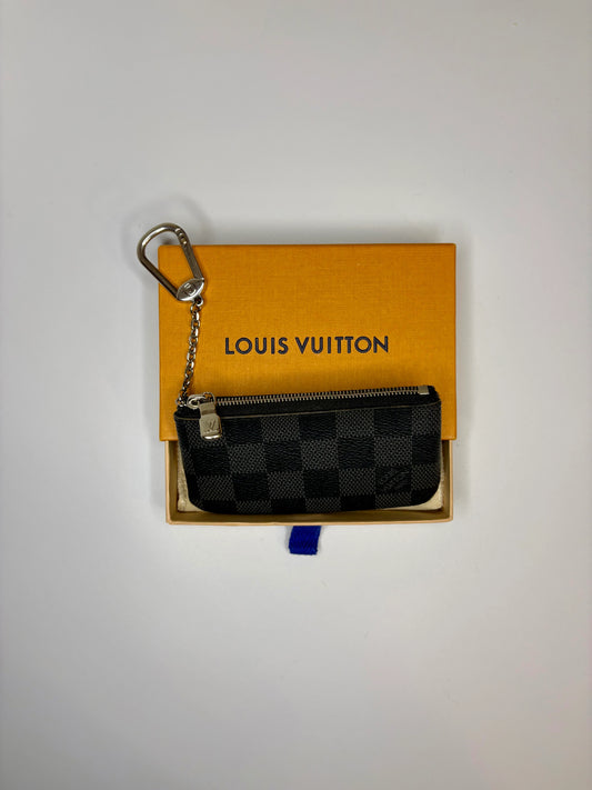 Louis Vuitton key pouch with a keychain on a Louis Vuitton box against a light gray background