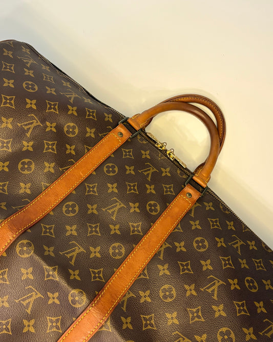 Close-up of the Louis Vuitton Keepall 55 showing the leather trim, yellow stitching and monogram canvas with aged patina.