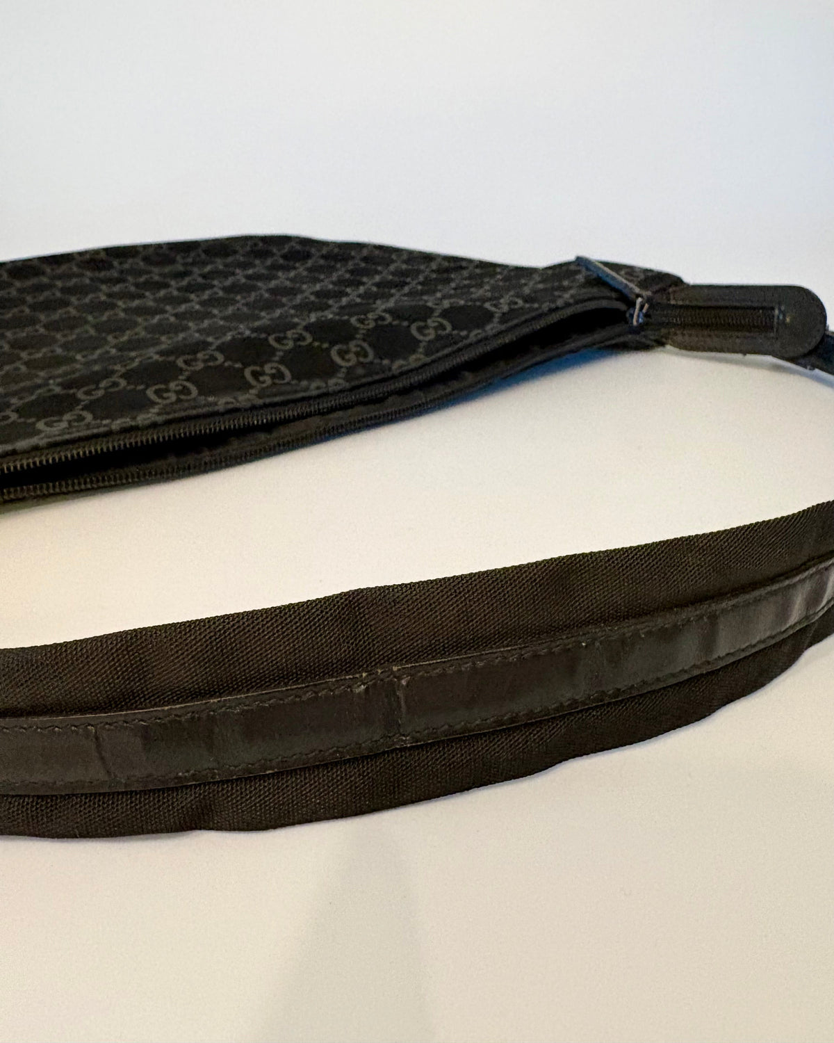 Side view of the black Gucci suede bag, highlighting the curve of the body and the leather strap detail.