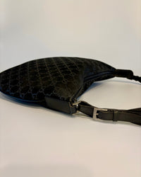 Side view of the black Gucci suede bag, highlighting the curve of the body and the leather strap detail.