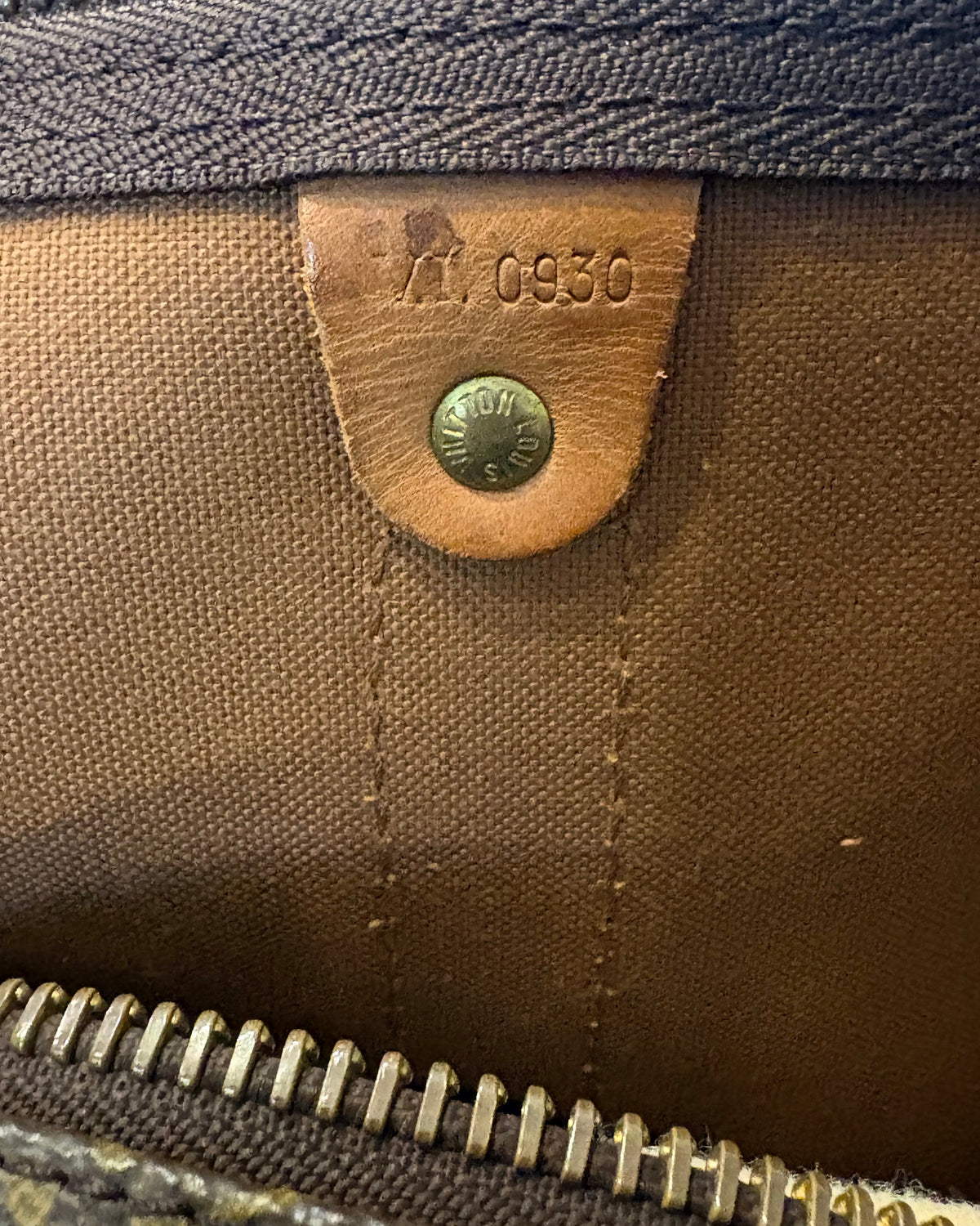 Interior view of the Louis Vuitton Keepall Bandoulière 55 showing the leather tab with date code VI0930 stamped inside.
