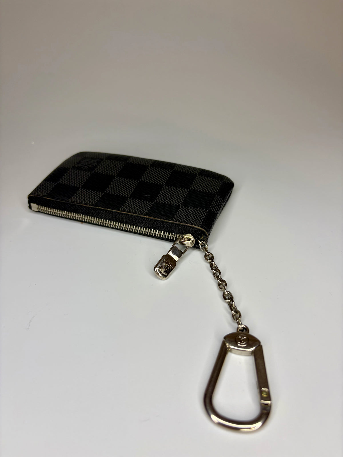 Black checkered keychain pouch with a metal carabiner on a white background