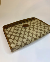 This Gucci GG canvas pouch shows its elegant, slim shape. The classic monogram and brown leather trim create a timeless and refined look.
