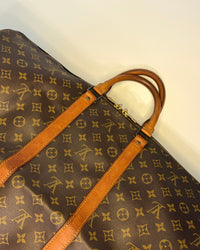 Close-up of the Louis Vuitton Keepall 55 showing the leather trim, yellow stitching and monogram canvas with aged patina.
