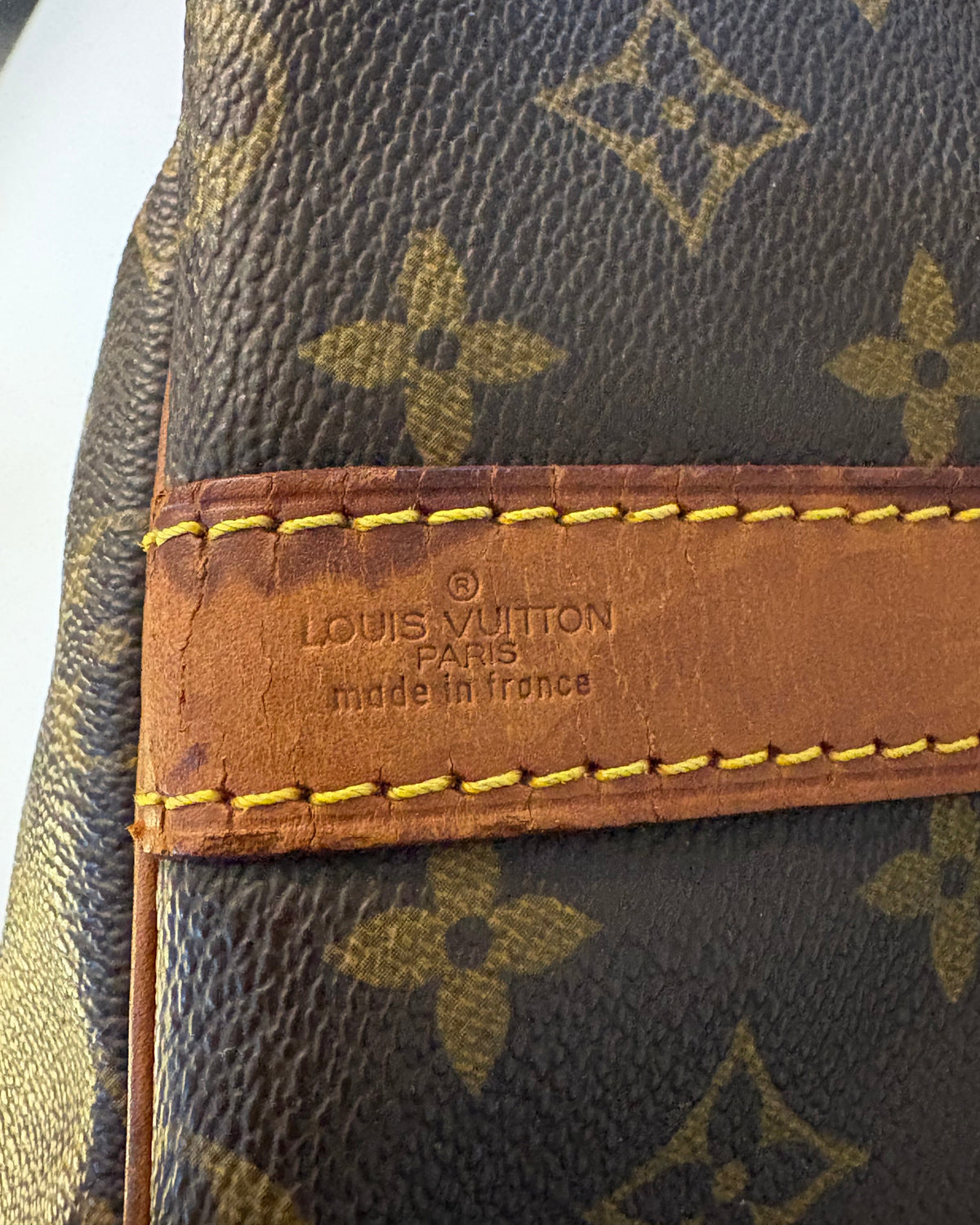 A vintage Louis Vuitton Keepall Bandoulière 55 in monogram canvas, shown from the front with natural patina on the leather handles.