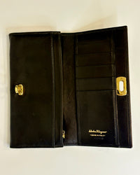 Black Salvatore Ferragamo leather wallet with gold Gancini clasp, displayed closed on a clean light background