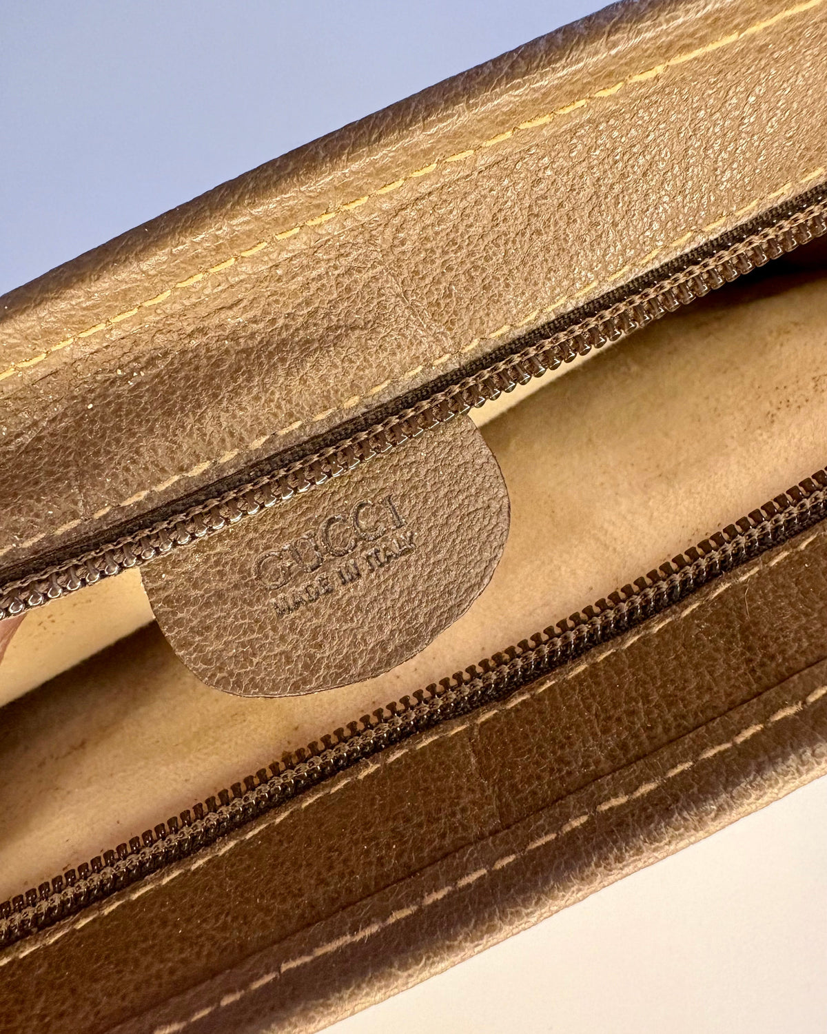 Close-up of the inner Gucci leather tag stamped “Made in Italy” inside the vintage GG Supreme pouch.