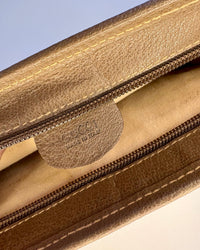Close-up of the inner Gucci leather tag stamped “Made in Italy” inside the vintage GG Supreme pouch.