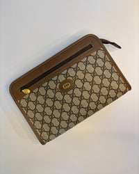 Angled top view of the vintage Gucci GG Supreme pouch highlighting the gold zipper pull and leather trim.